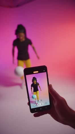 Vertical-Video-Studio-Shot-Of-Female-Footballer-Recording-Video-For-Social-Media-On-Mobile-Phone-Teaching-Ball-Skills